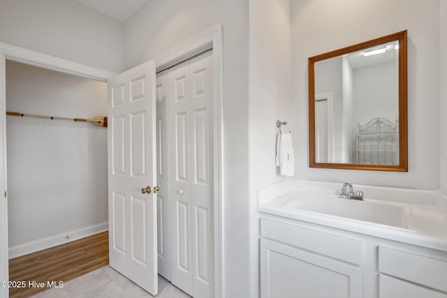 bathroom with a closet, vanity, and baseboards