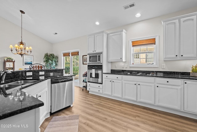 kitchen featuring stainless steel appliances, a sink, decorative light fixtures, and white cabinets