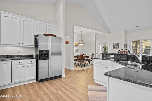 kitchen with dark stone countertops, a sink, white cabinets, and stainless steel fridge with ice dispenser