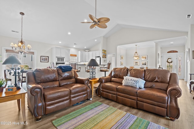 living area featuring high vaulted ceiling, light wood-type flooring, visible vents, and recessed lighting