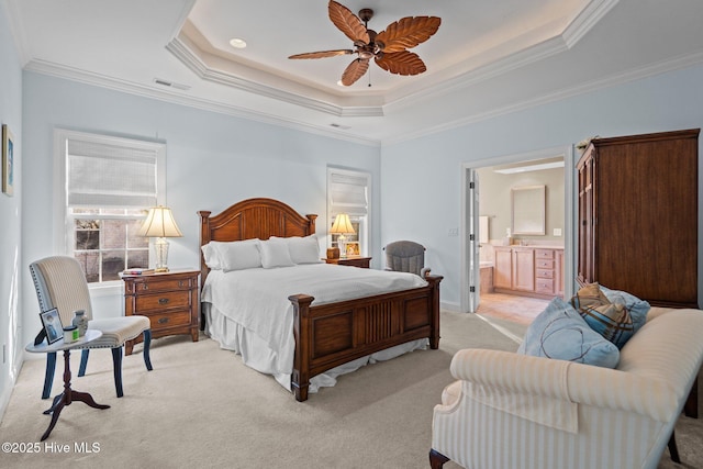 bedroom with a tray ceiling, visible vents, ornamental molding, light carpet, and ensuite bath