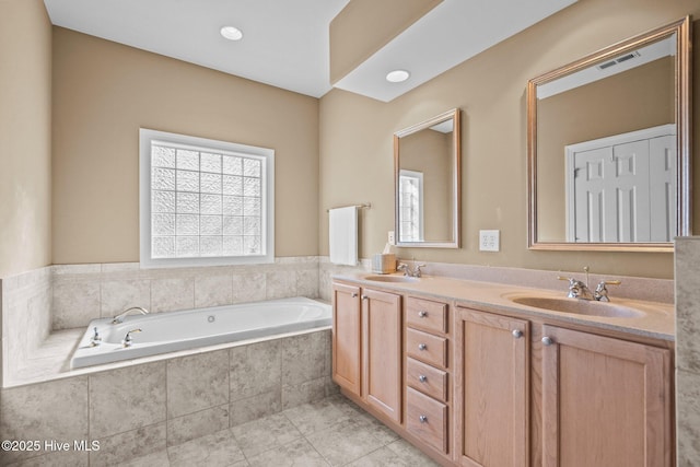 bathroom with a garden tub, double vanity, a sink, and tile patterned floors