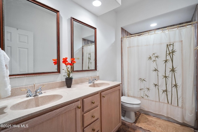 bathroom featuring double vanity, a sink, and toilet