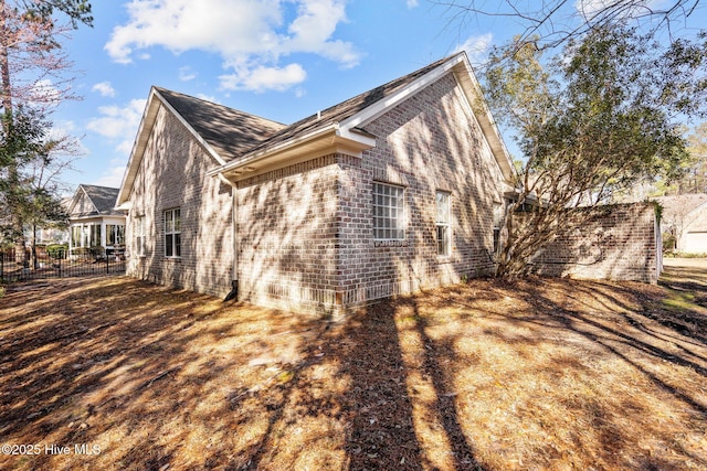 view of side of home featuring brick siding and fence