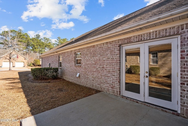 view of side of property featuring brick siding, a patio, and french doors