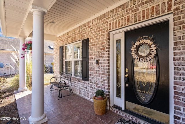 entrance to property with covered porch and brick siding