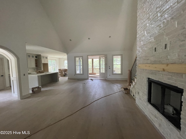 241 Juniper Creek Blvd, Pinehurst, NC 28374 - unfurnished living room featuring high vaulted ceiling, stairway, arched walkways, baseboards, and light wood-style floors