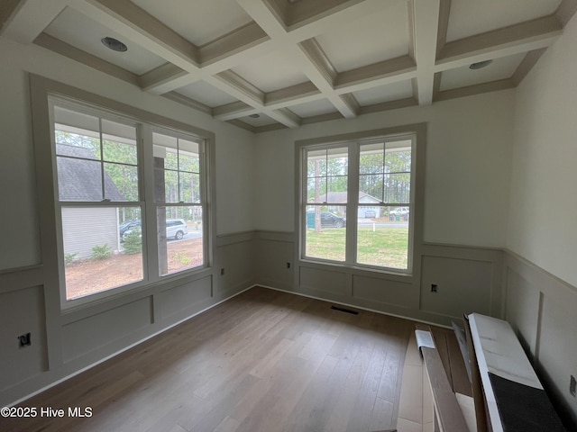 spare room with coffered ceiling, beam ceiling, wood finished floors, and a wainscoted wall