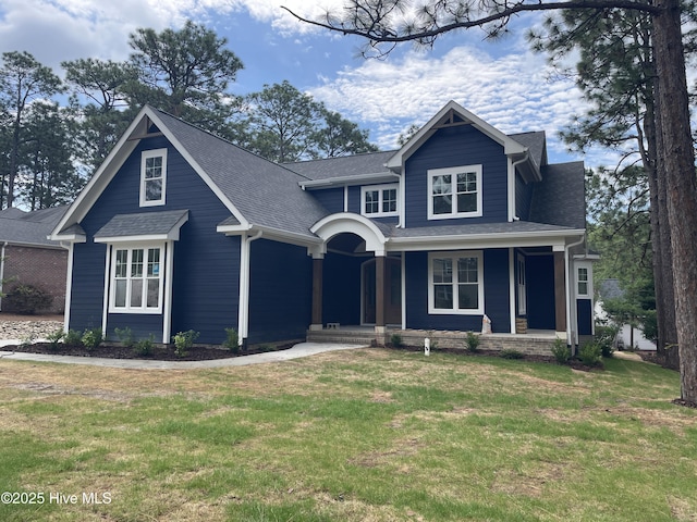 craftsman-style house featuring a front lawn, a shingled roof, and covered porch