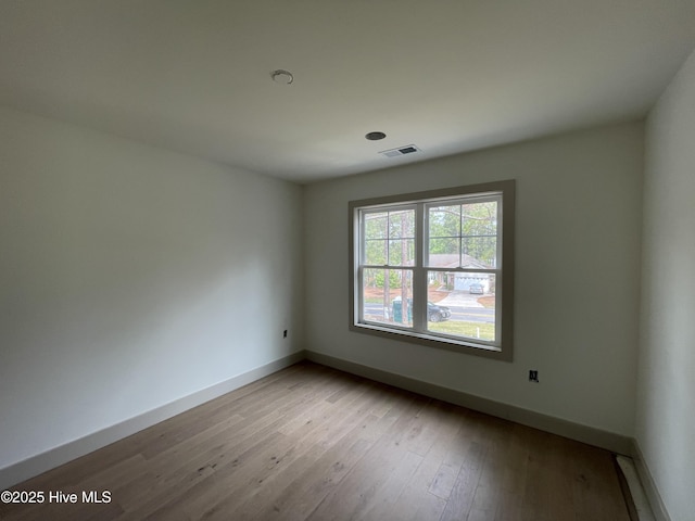 spare room with baseboards and wood finished floors