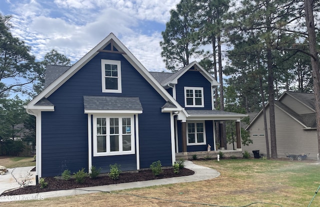 view of front of home with a porch, roof with shingles, and a front lawn