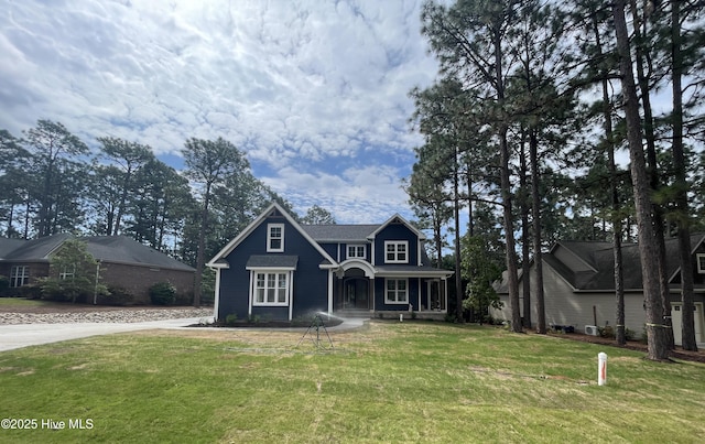 traditional-style house featuring covered porch, a front lawn, and driveway
