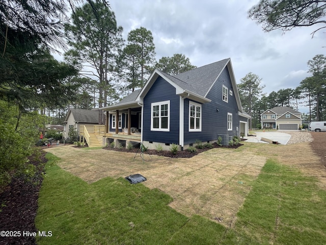 view of side of home with a porch, driveway, a lawn, a garage, and cooling unit