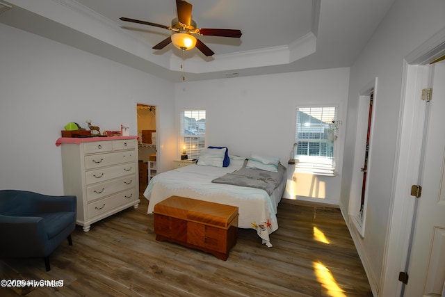 bedroom with a raised ceiling, crown molding, dark hardwood / wood-style floors, and ceiling fan