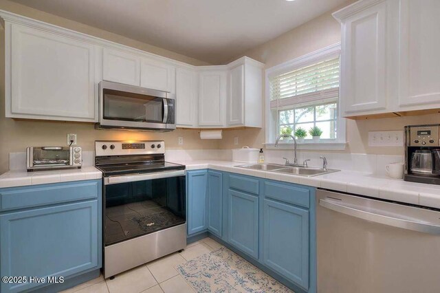 106 NE 62nd St, Oak Island, NC 28465 - kitchen featuring appliances with stainless steel finishes, a sink, blue cabinets, and white cabinetry