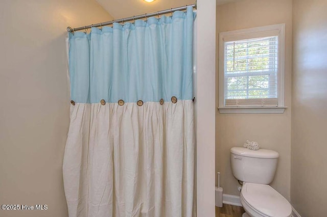 full bath with a shower with curtain, baseboards, and toilet