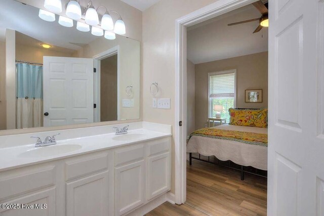 bedroom featuring baseboards, lofted ceiling, ensuite bath, light wood-type flooring, and a sink