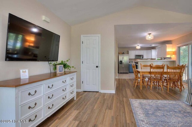 living area with visible vents, lofted ceiling, light wood-style flooring, and a ceiling fan