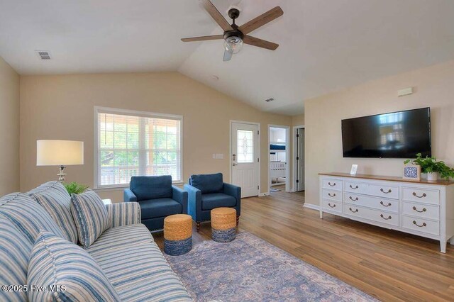 living room featuring lofted ceiling, visible vents, a wealth of natural light, and wood finished floors