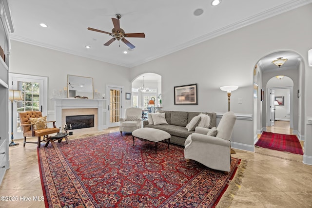 living room featuring crown molding, ceiling fan with notable chandelier, and a high end fireplace