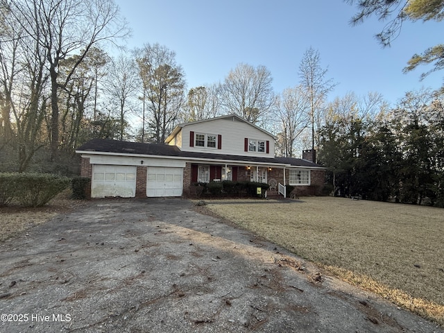 traditional-style house featuring aphalt driveway, an attached garage, covered porch, brick siding, and a front yard