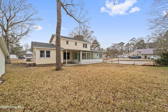 rear view of property featuring a yard, a patio area, and a sunroom