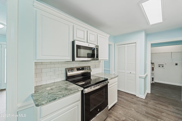 kitchen with white cabinetry, stainless steel appliances, wood-type flooring, and light stone counters