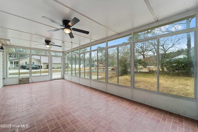 unfurnished sunroom featuring ceiling fan, a wall unit AC, and a wealth of natural light