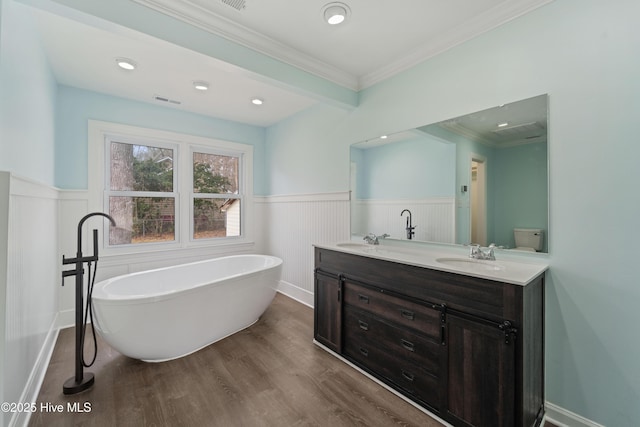 bathroom with hardwood / wood-style floors, a bathtub, vanity, toilet, and crown molding