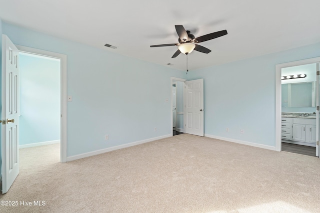 unfurnished bedroom with ensuite bath, light colored carpet, and ceiling fan