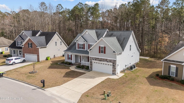 traditional-style house with a garage, covered porch, central AC, stone siding, and concrete driveway