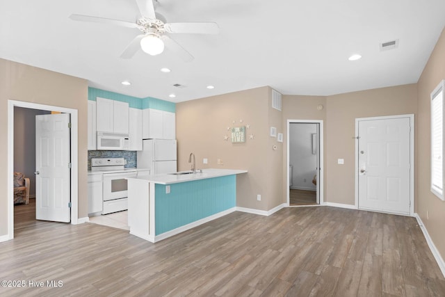 kitchen featuring sink, backsplash, white cabinets, white appliances, and light wood-type flooring