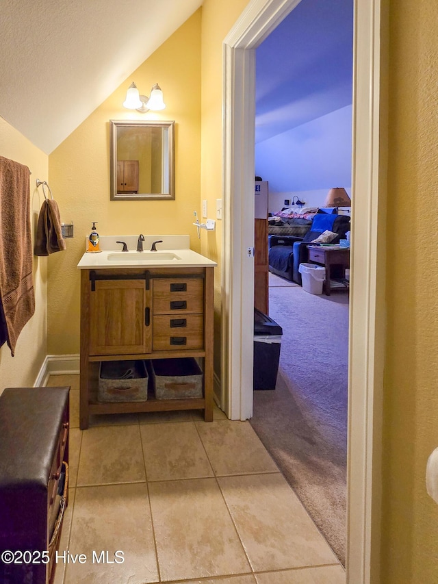 bathroom with tile patterned flooring, vanity, and lofted ceiling