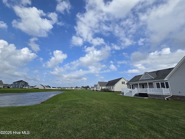 view of yard with a water view and covered porch