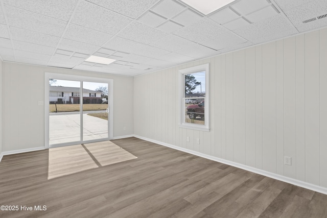 spare room featuring a wealth of natural light, visible vents, baseboards, and wood finished floors