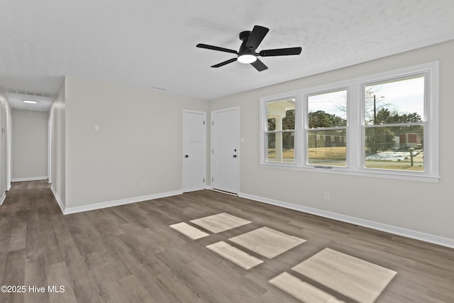 unfurnished room featuring visible vents, wood finished floors, attic access, and baseboards