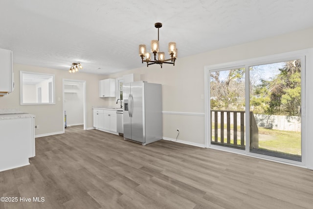 kitchen with white cabinets, wood finished floors, stainless steel appliances, light countertops, and pendant lighting