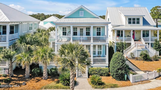 raised beach house featuring a porch, metal roof, a standing seam roof, and stairs