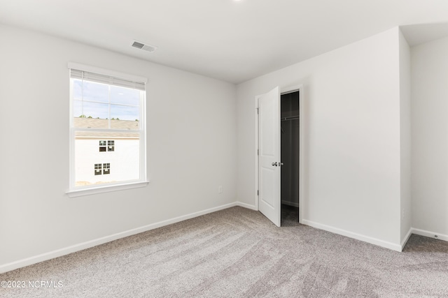 unfurnished bedroom featuring light carpet, a spacious closet, and a closet