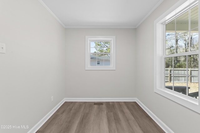 spare room featuring crown molding, dark wood-type flooring, visible vents, and baseboards