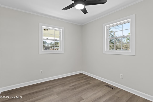 spare room featuring baseboards, crown molding, visible vents, and wood finished floors