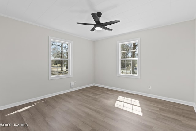 unfurnished room with a healthy amount of sunlight, baseboards, visible vents, and wood finished floors