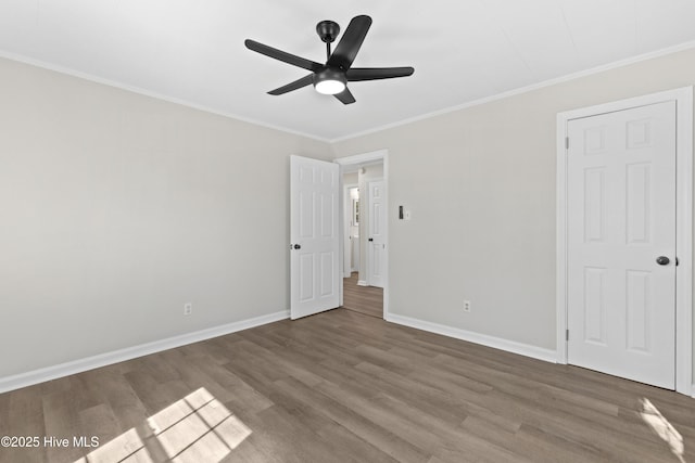 empty room with ceiling fan, ornamental molding, wood finished floors, and baseboards