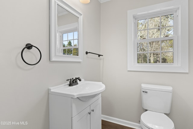 half bath featuring toilet, vanity, and baseboards