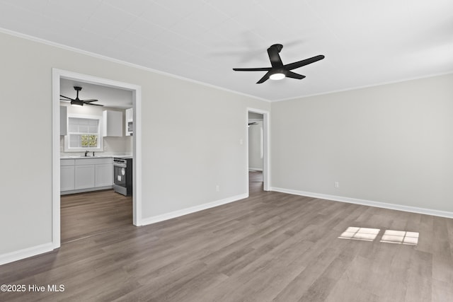 unfurnished living room with a sink, wood finished floors, baseboards, a ceiling fan, and crown molding