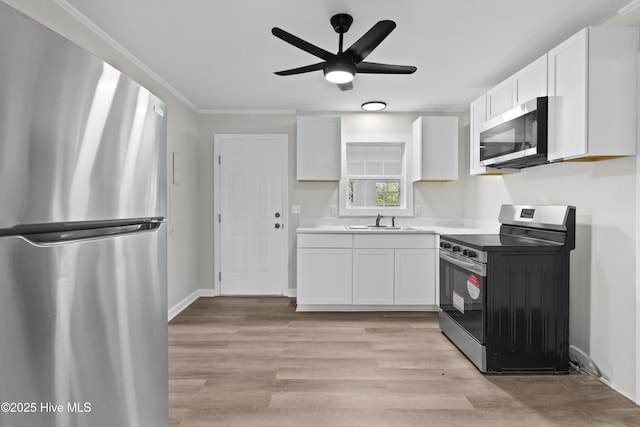 kitchen featuring stainless steel appliances, white cabinetry, a sink, and light wood finished floors