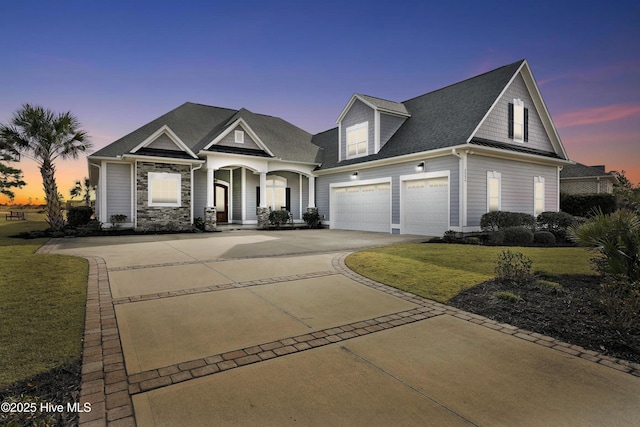 view of front of property featuring a garage, driveway, stone siding, and a front yard