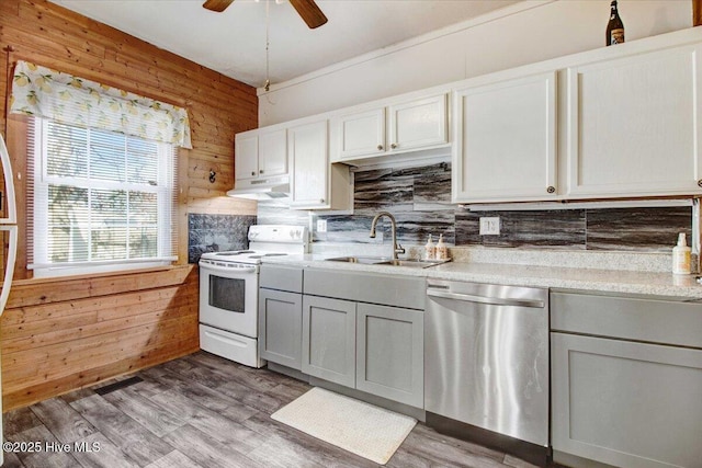 kitchen with sink, electric range, wooden walls, and dishwasher