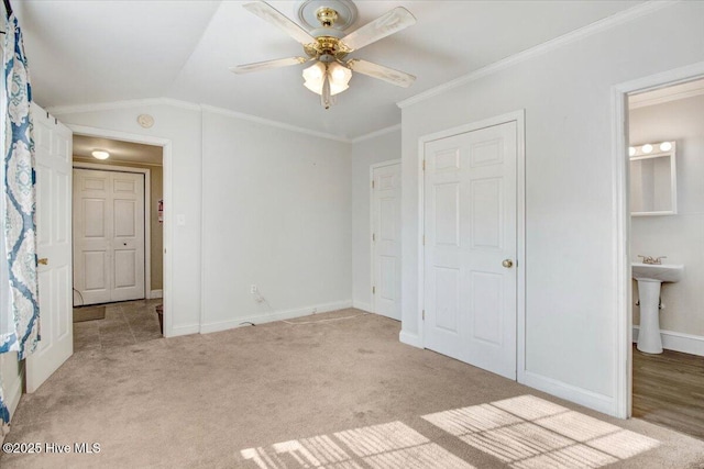 unfurnished bedroom with vaulted ceiling, ceiling fan, crown molding, light carpet, and ensuite bath