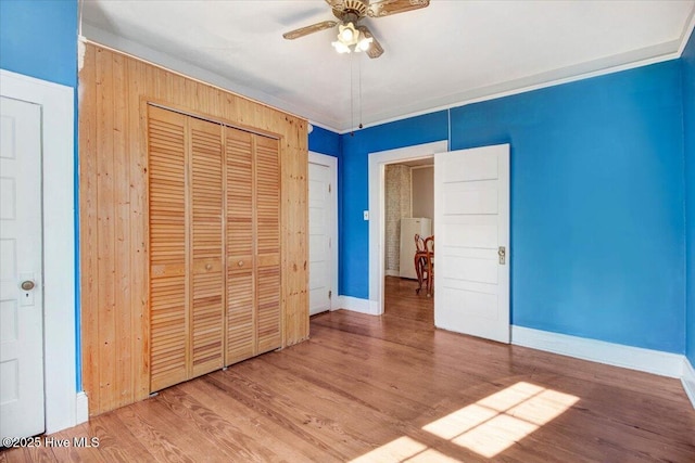 unfurnished bedroom featuring ceiling fan, wood-type flooring, and a closet